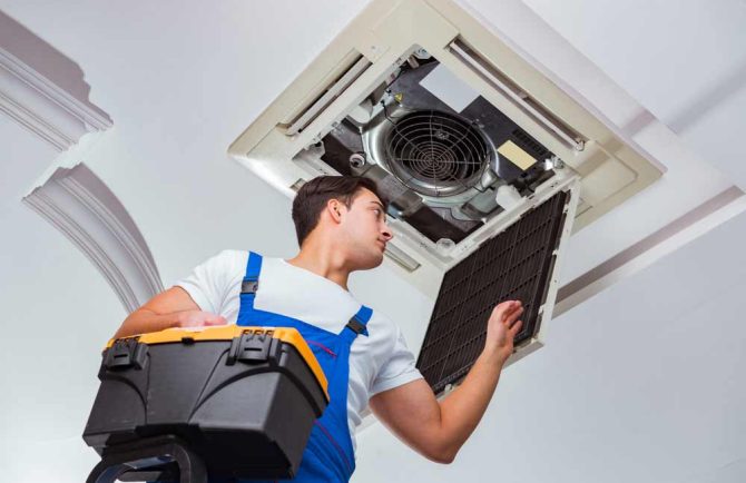 Technician Fixing A Ceiling Air Conditioning Unit — Instachill in Gold Coast, QLD