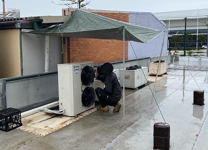 Technician Repairing Air Condition While Raining — Instachill in Gold Coast, QLD